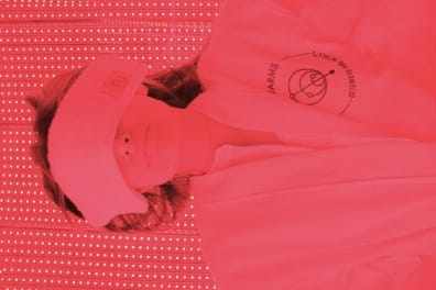 Person in a white robe and eye mask undergoing red light therapy.