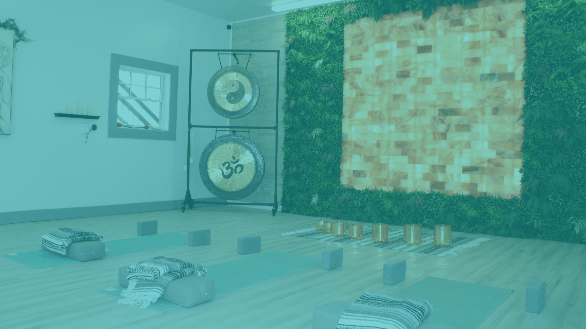 Himalayan salt wall studio set up with yoga mats, blocks, blankets and instruments such as gongs and singing bowls.